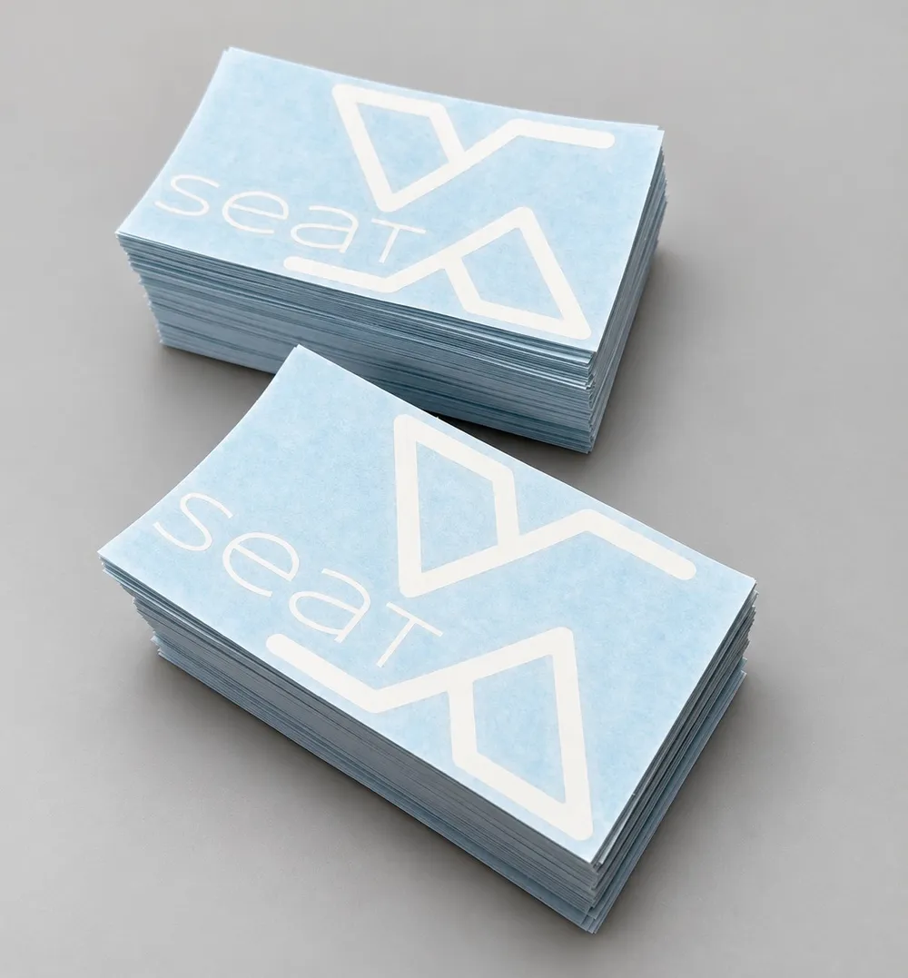 White cut-vinyl logo decals on transfer tape, stacked at Vaderwerks
