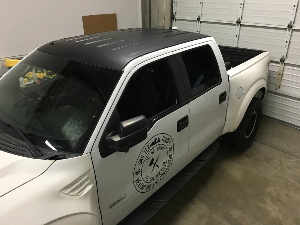 White Ford F-150 with black roof wrap and door logo decal for a local trade company
