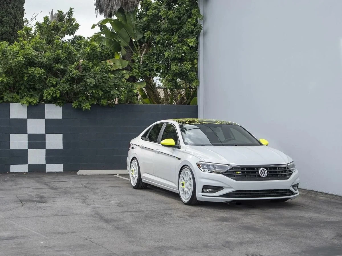 White Volkswagen Jetta with neon yellow mirrors and roof graphics by Vaderwerks